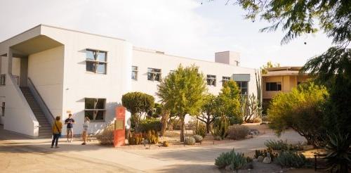 Several students chat outside the large white building of Broad Hall.